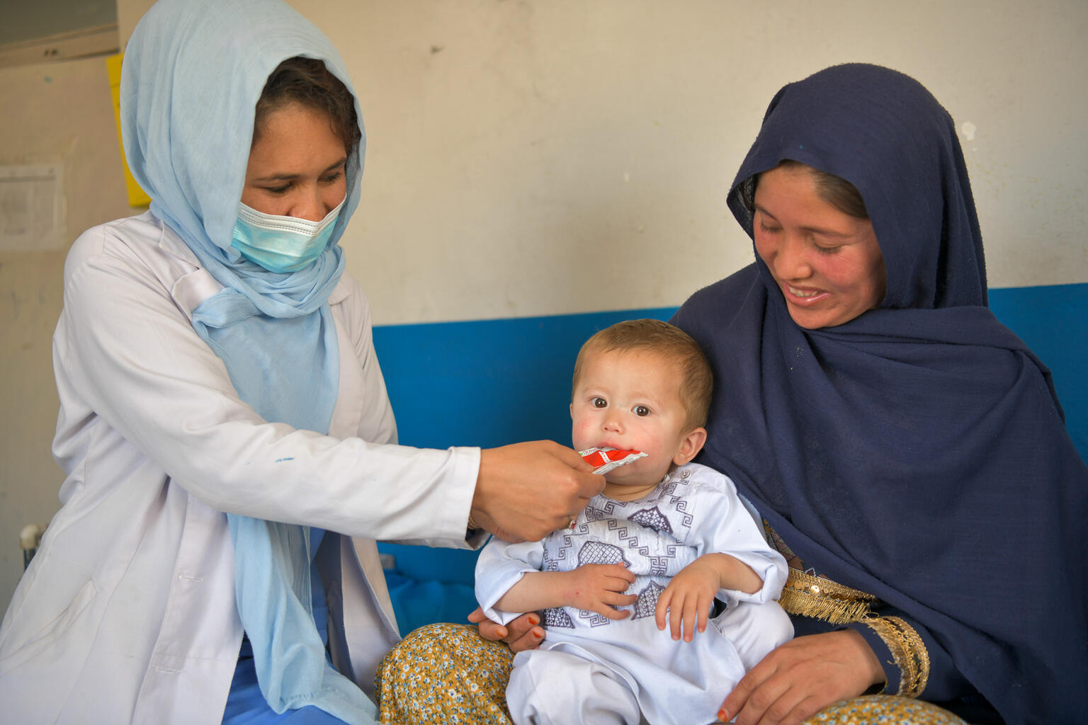  a nurse feeds 18-month-old Mahdi a sachet of ready-to-use therapeutic food (RUTF)